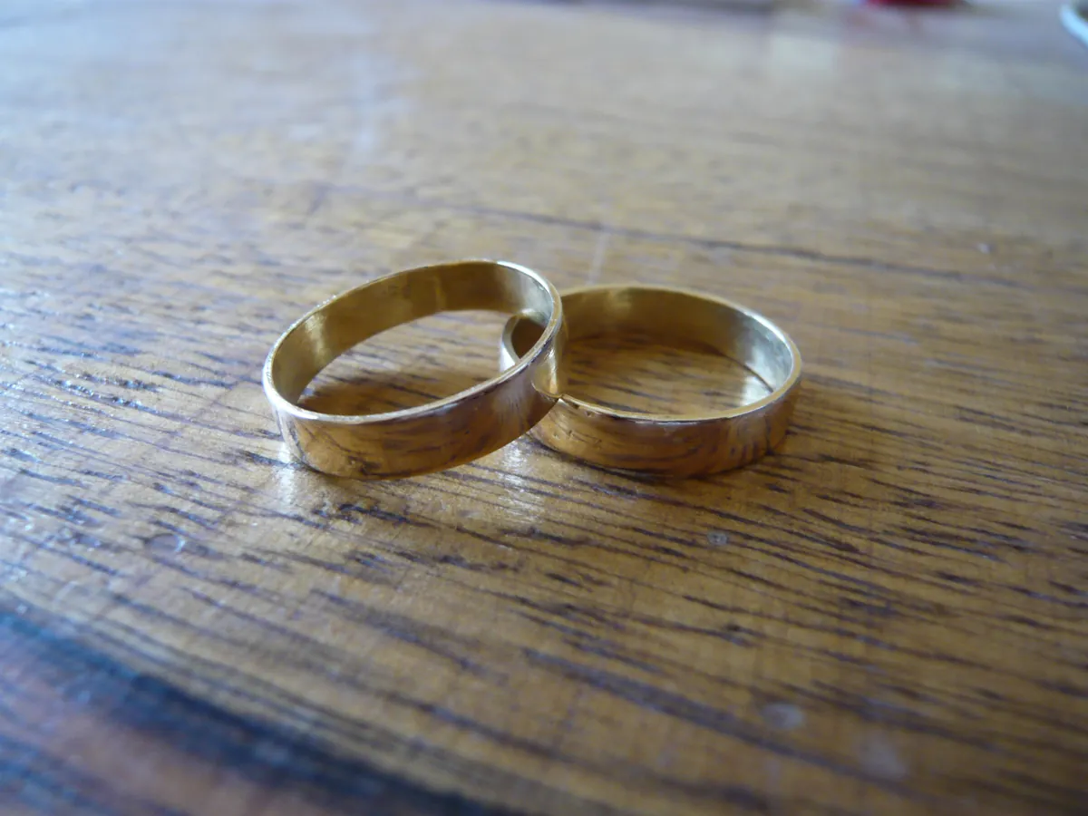 Two plain gold wedding rings resting on a wooden table