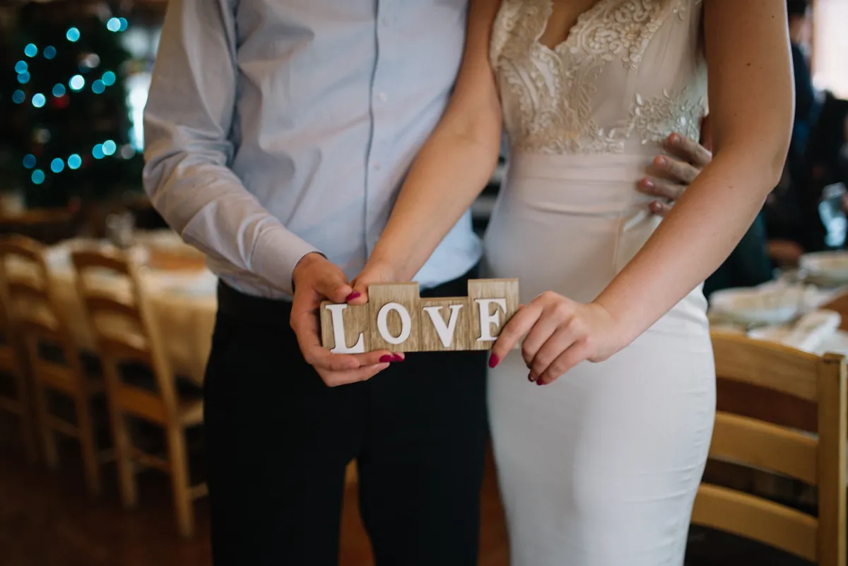Couple in wedding clothes holding wooden letters that spell LOVE